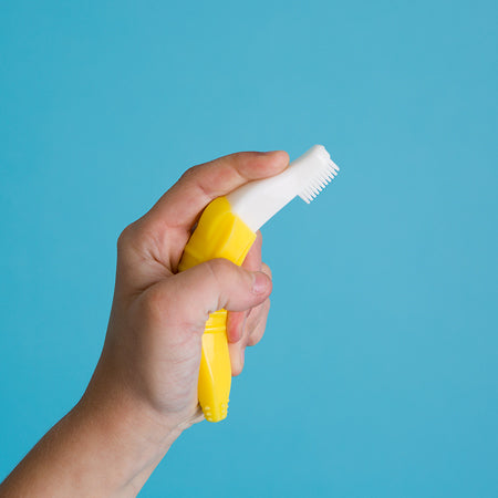 A cute toddler holding Baby Banana Toddler Toothbrush